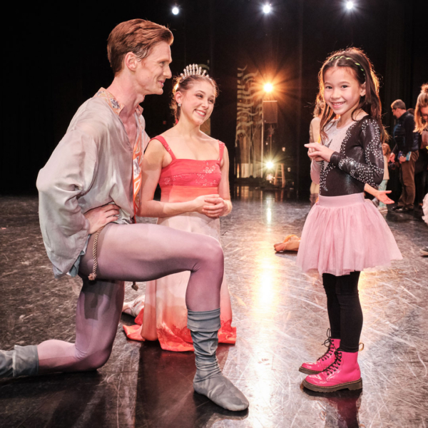 Little girl gets to meet two ballet dancers on stage after a performance.